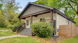 Ein eingeschossiges Haus mit Veranda, einer Treppe zum Eingang und einem Holzzaun.