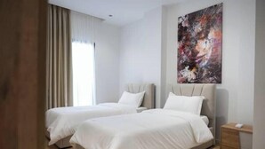 A hotel room with two beds, a large abstract painting on the wall, and a bedside table with a lamp. - Barrikada-E – Central Apartments with French Balcony & Netflix in Tirana (Tiranë)