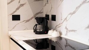 A kitchen with a black coffee maker, a white kettle, and a marble backsplash. - Barrikada-E – Central Apartments with French Balcony & Netflix in Tirana (Tiranë)