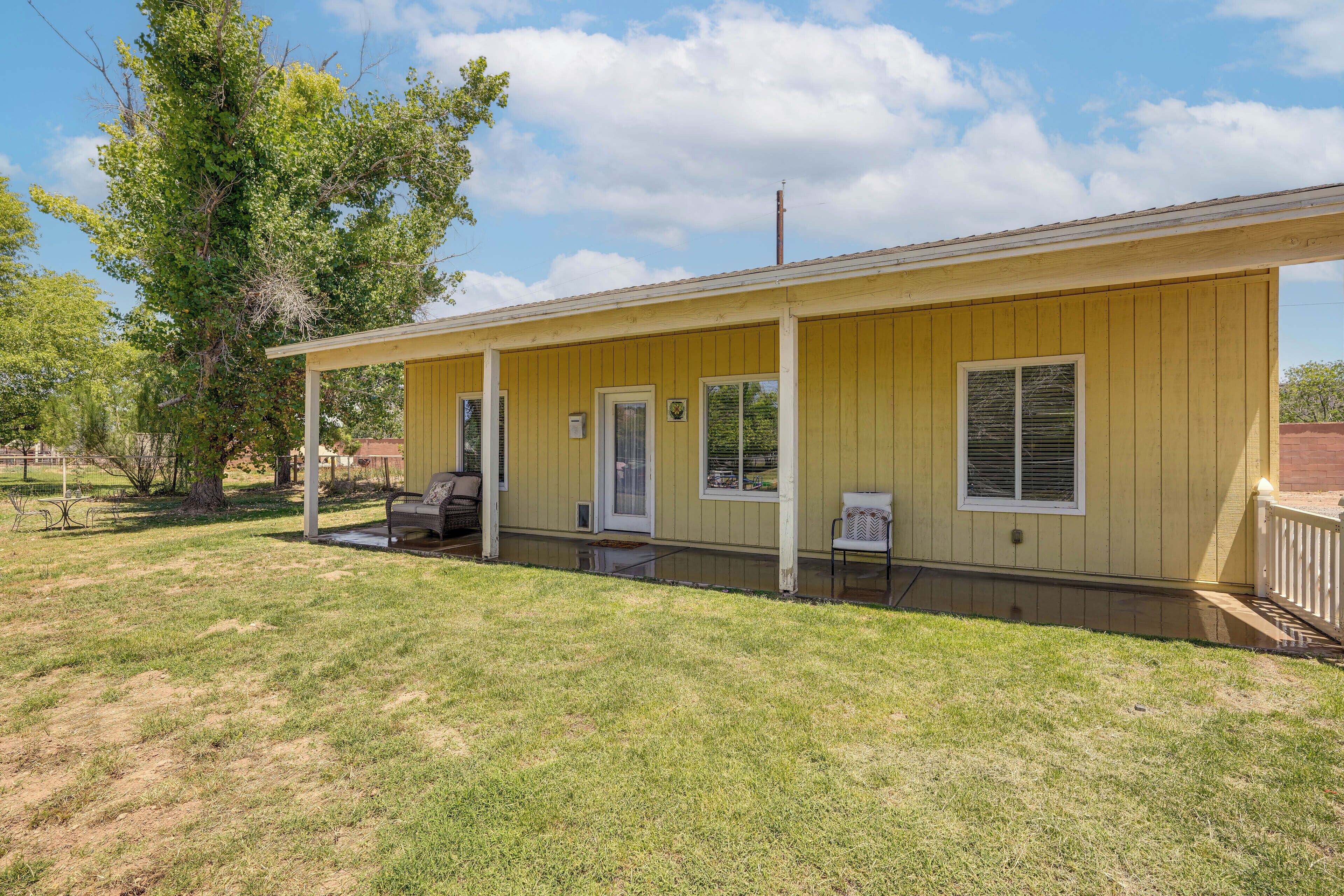 A yellow single-story building with a covered porch, a door, and a window.