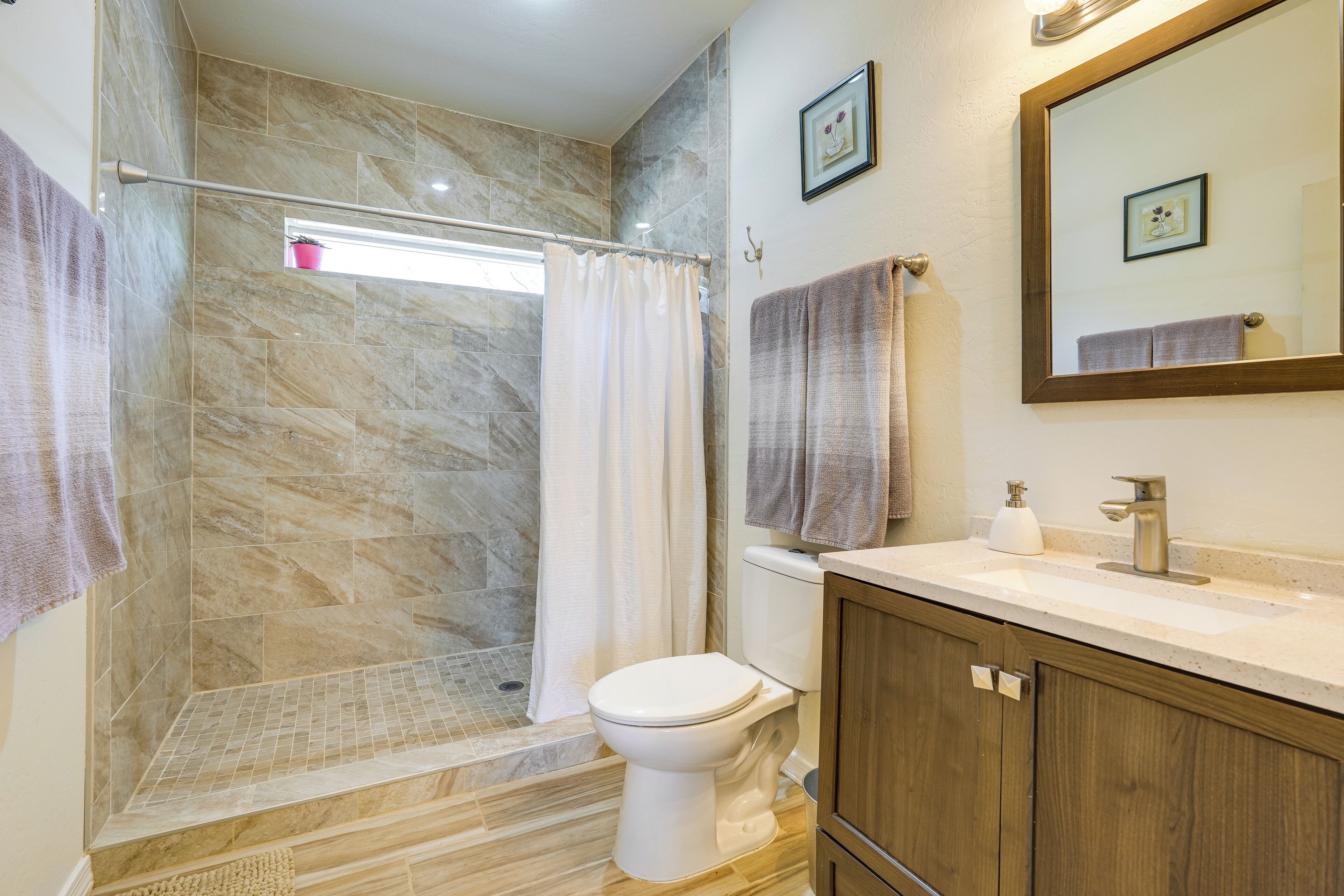 Une salle de bain équipée d’une douche, de toilettes, d’un lavabo et de meubles en bois.