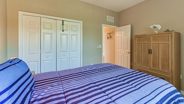Un dormitori amb un llit, un armari i una porta que dona a una altra habitació.