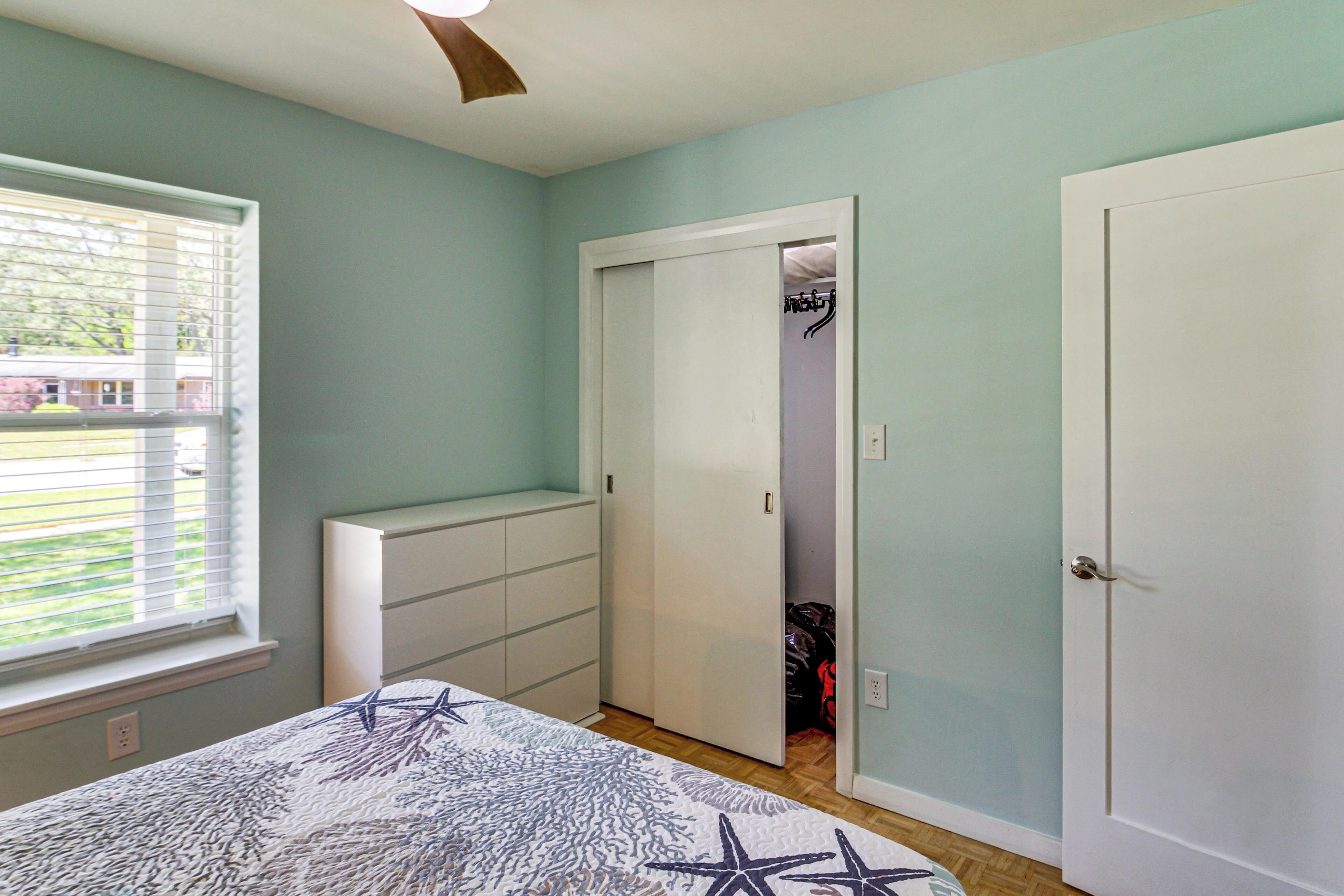 Un dormitorio con cama, armario, closet y ventana con persianas.