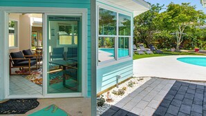 Une maison avec une porte vitrée donnant sur un patio aménagé avec une piscine, du mobilier d’extérieur et un jardin.