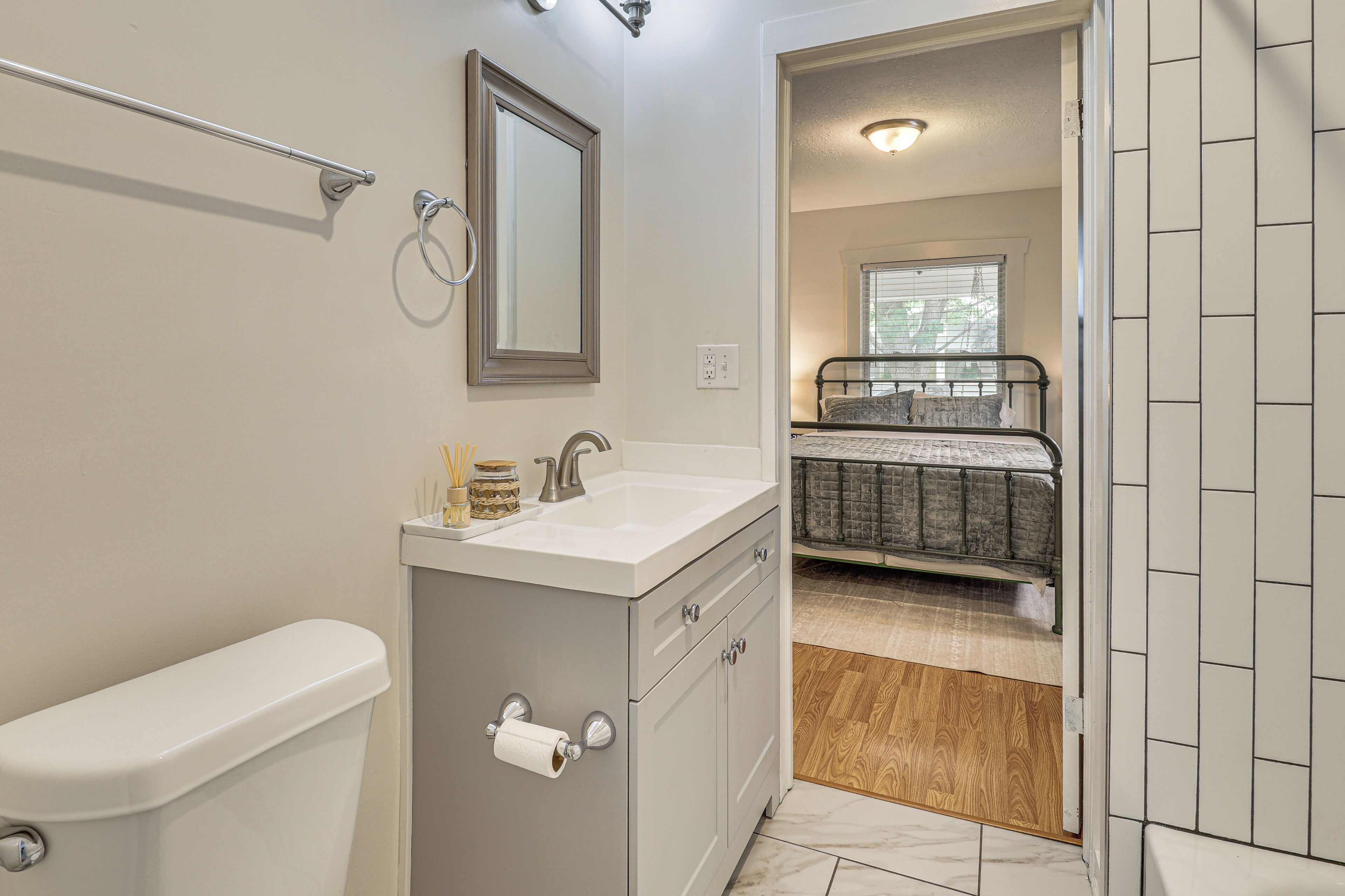 A bathroom with a toilet, sink, mirror, and a shower area.