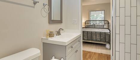 A bathroom with a toilet, sink, mirror, and a shower area.