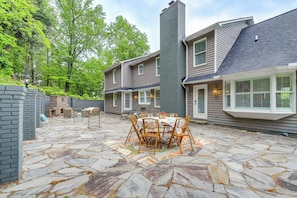 A patio with stone flooring, a table with chairs, and a brick wall.