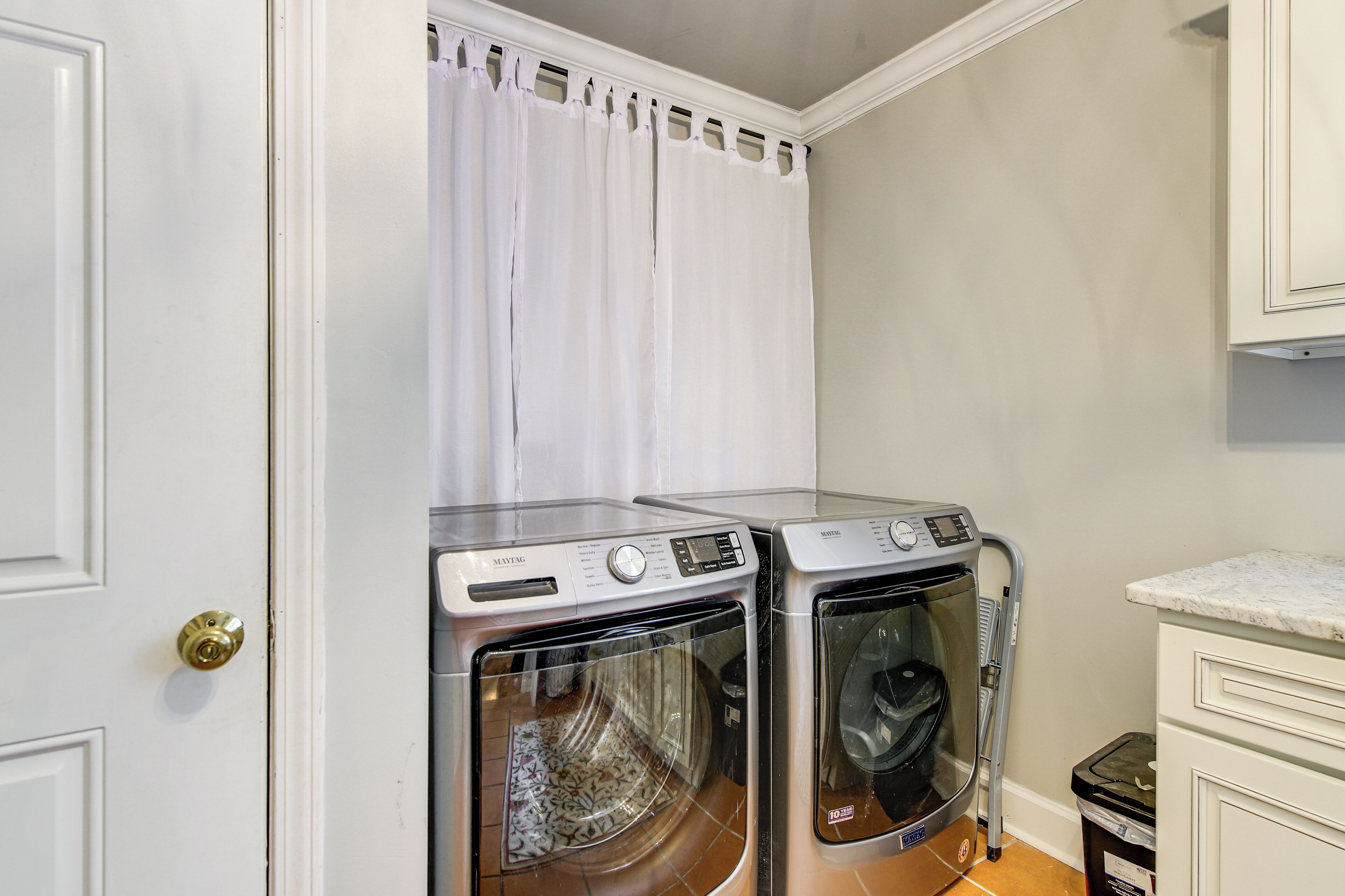 A laundry room with two front-loading washing machines, a white door, and a tiled floor.