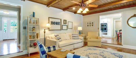A living room with a wooden ceiling, a sofa, a coffee table, and a dining area with chairs.