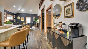 Uma cozinha moderna com cafeteira, banquetas de bar e uma área de refeições com cadeiras.