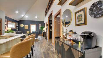 Una cocina moderna con cafetera, taburetes de bar y zona de comedor con sillas.