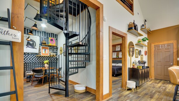 Um interior moderno com escada em espiral, piso de madeira e área de jantar com cadeiras e mesa.