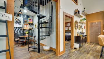 Um interior moderno com escada em espiral, piso de madeira e área de jantar com cadeiras e mesa.