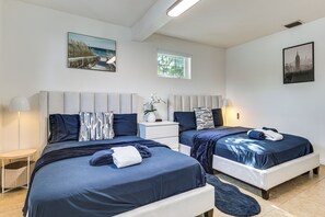 A hotel room with two beds, a nightstand, a lamp, and artwork on the walls.