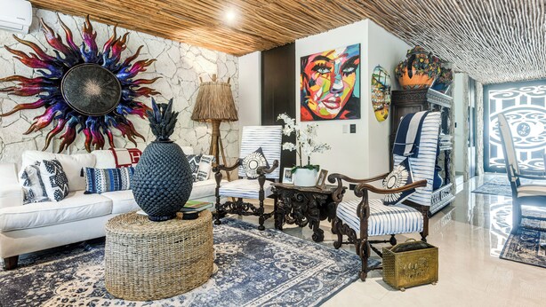 A living room with a white sofa, a blue patterned rug, a decorative sun-like wall piece, and a large abstract painting. - Private Xpu Ha Beach Access: 6,700-sq-ft Villa (Xpu-Ha)