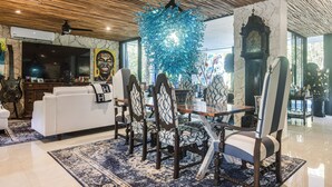 A dining area with a chandelier, a clock, and a large window. - Private Xpu Ha Beach Access: 6,700-sq-ft Villa (Xpu-Ha)