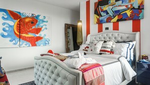 A bedroom with a tufted headboard bed, a large fish painting, and abstract art on the wall. - Private Xpu Ha Beach Access: 6,700-sq-ft Villa (Xpu-Ha)