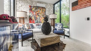 A modern living room with a stone wall, a colorful abstract painting, and a large window.