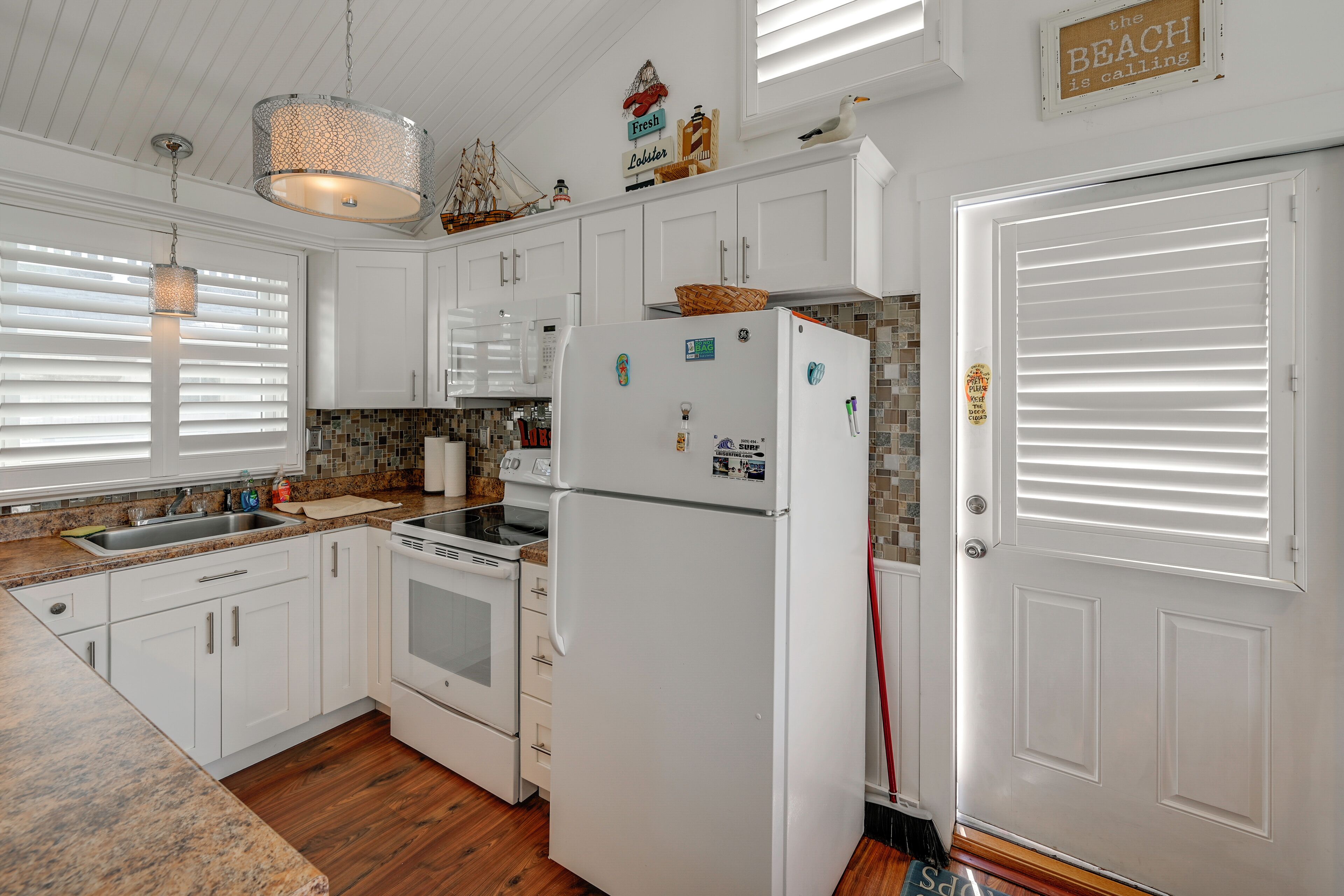 A kitchen with white cabinets, a refrigerator, a stove, and a sink.