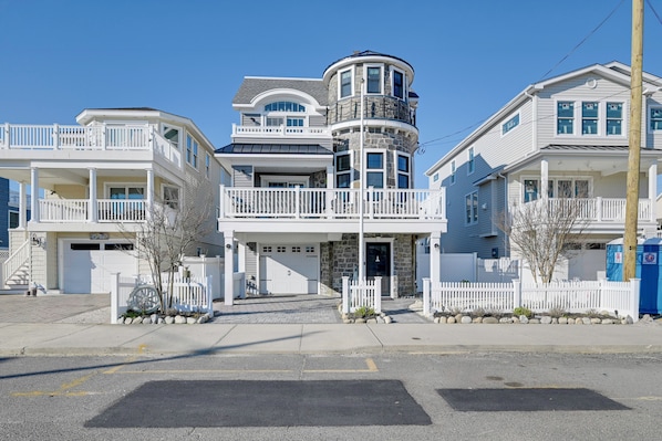 A multi-story residential building with a central tower, a covered front porch, and a garage.