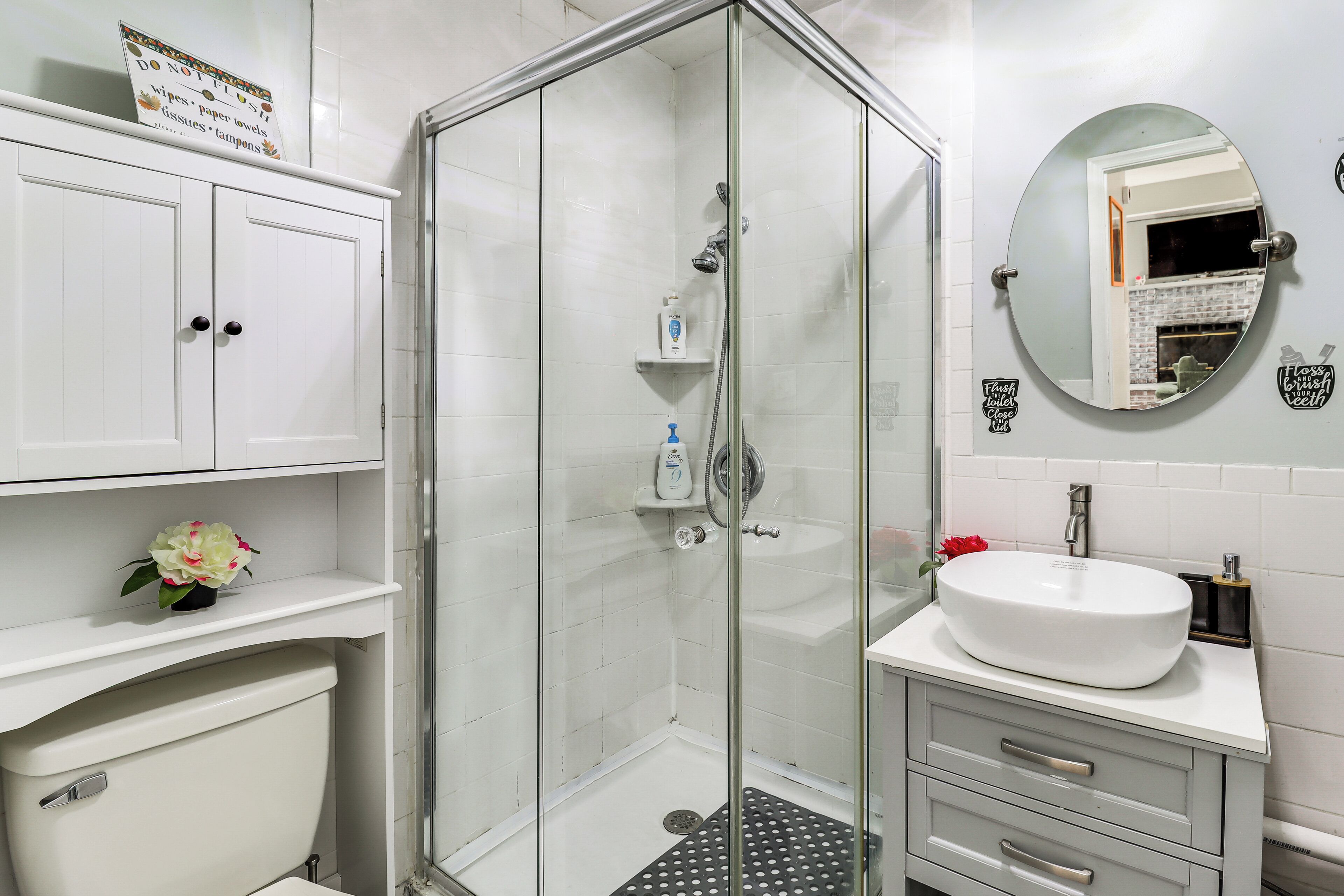 A bathroom with a glass-enclosed shower, a white sink, and a mirror.