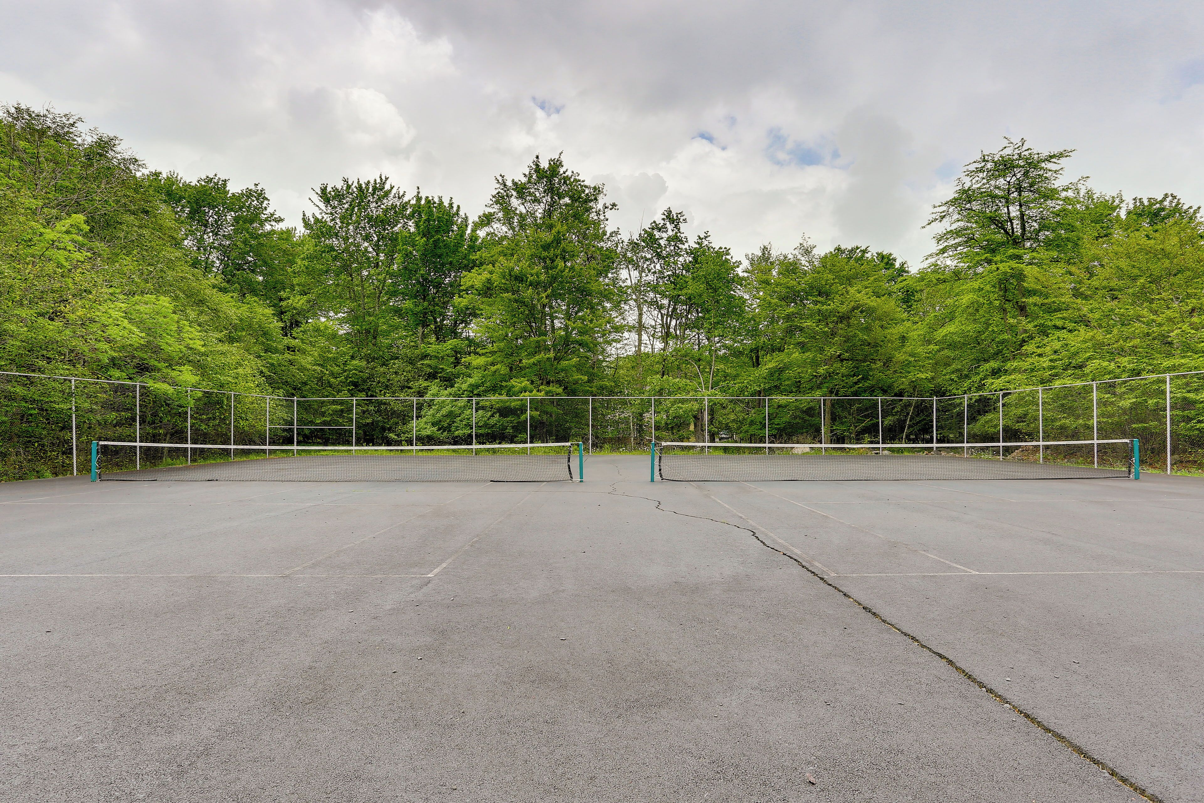 Ein Tennisplatz im Freien, umgeben von Bäumen.
