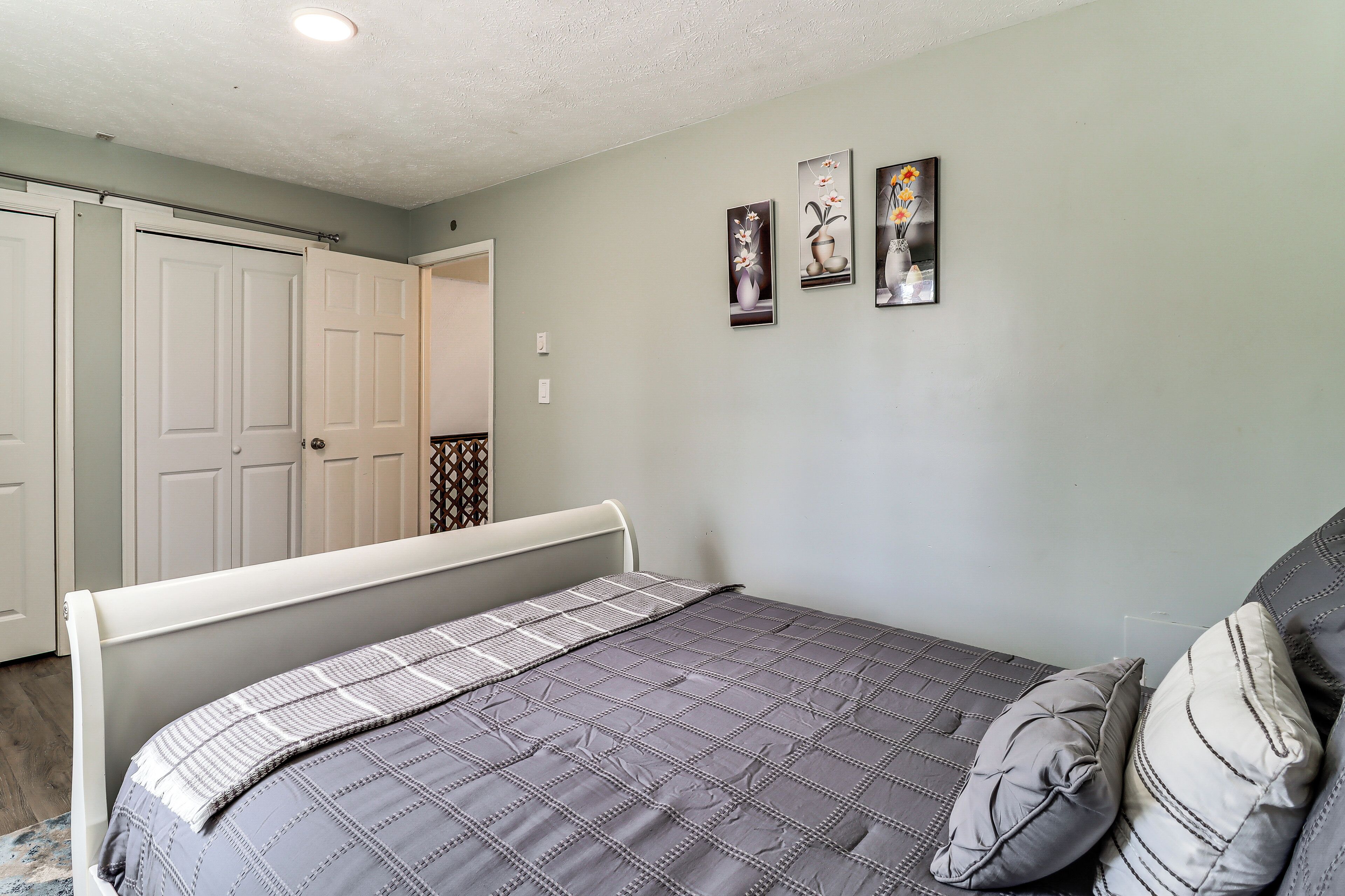 A bedroom with a bed, a door, and three wall-mounted pictures.