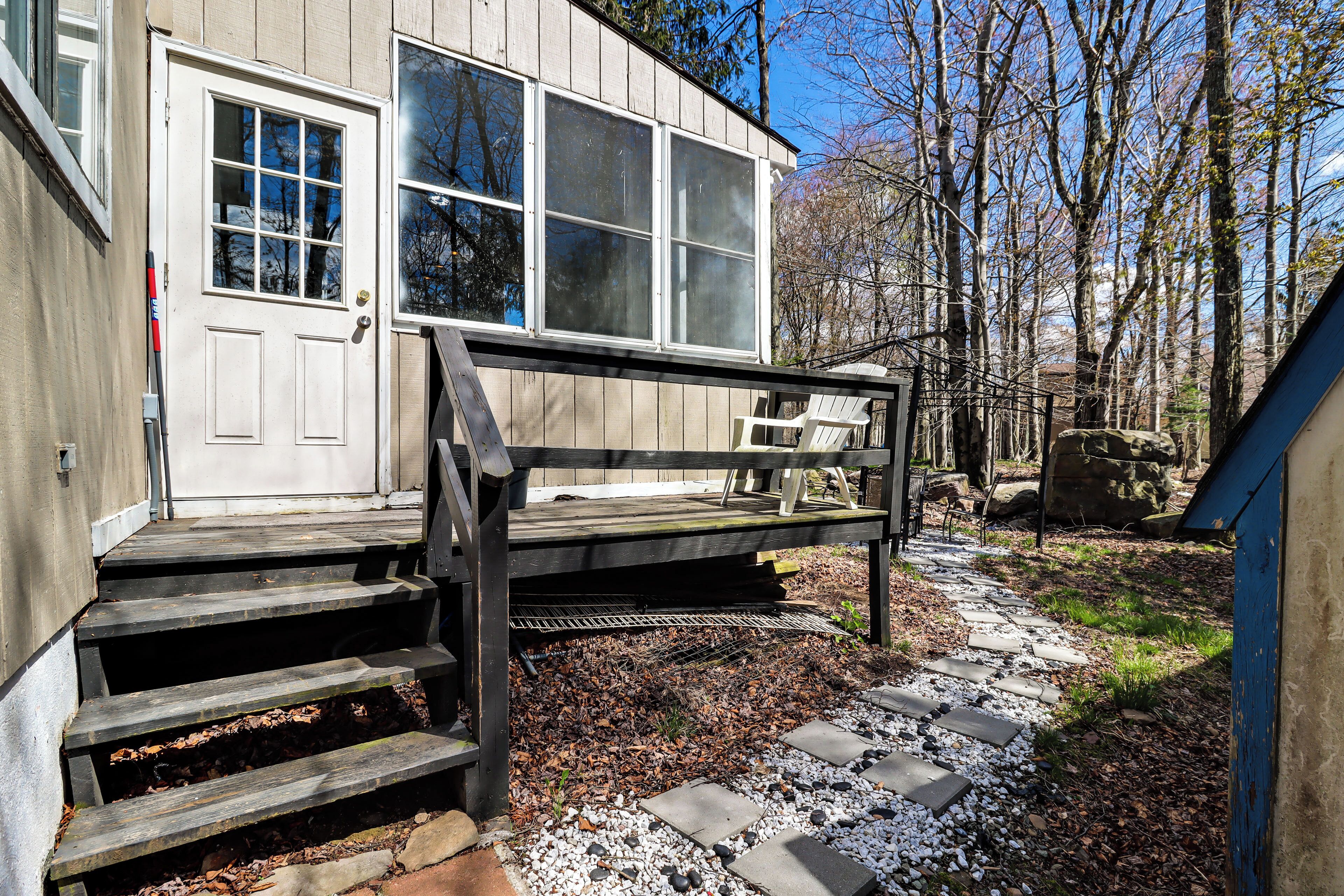 A wooden deck with steps leading to a building with large windows and a door.