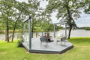 A covered outdoor deck with a table and chairs, overlooking a lake. - Private Dock + Decks: Lake O' the Pines Escape (Jefferson)