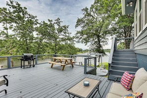 A wooden deck with a grill, picnic table, and outdoor seating area overlooking a body of water. - Private Dock + Decks: Lake O' the Pines Escape (Jefferson)