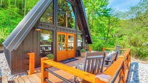 Eine Holzhütte mit einer Veranda, großen Fenstern und einer Fußmatte.