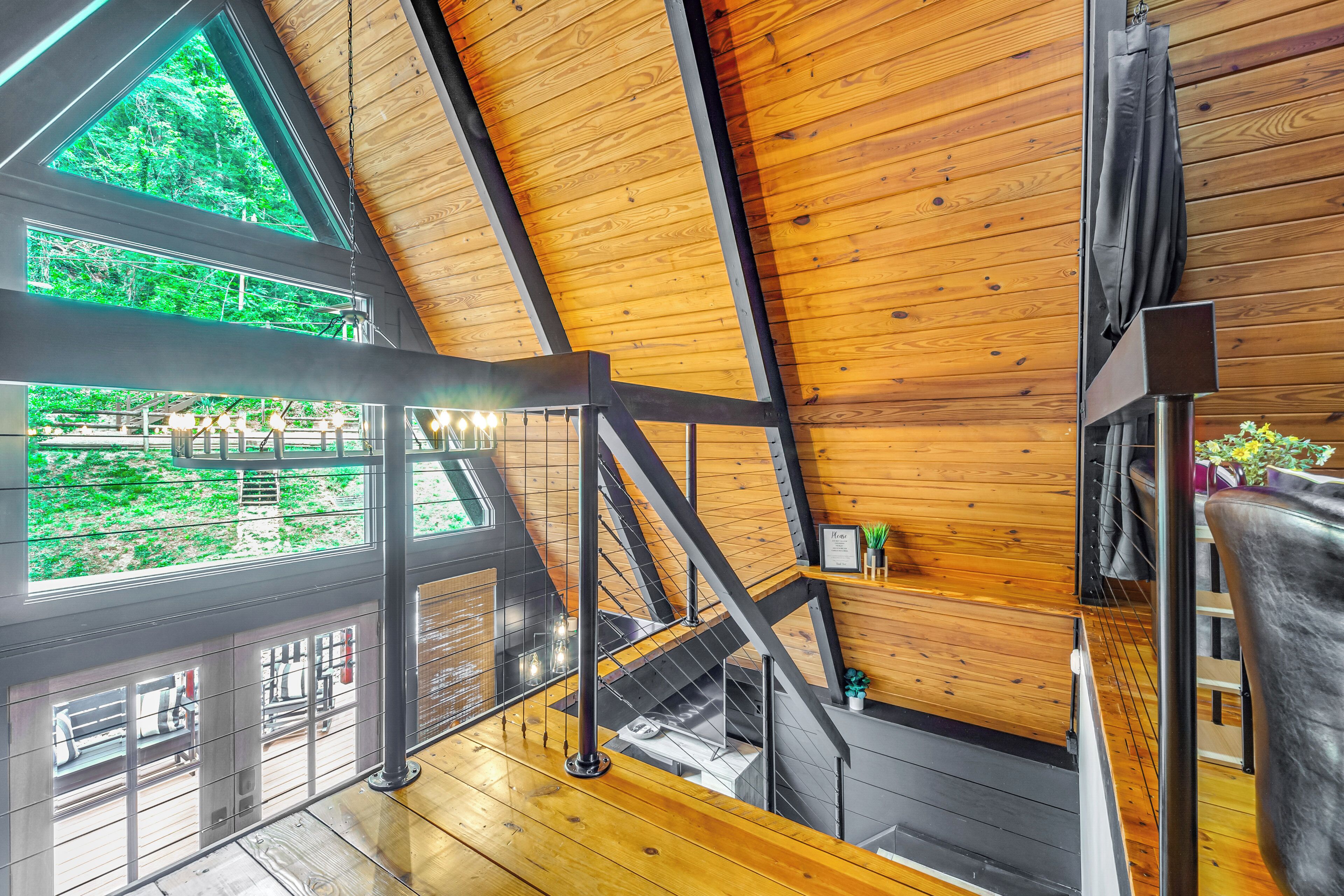 A wooden interior with a staircase, large windows, and a view of greenery outside.