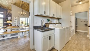 Una cucina con mobili bianchi, una lavatrice integrata e un soffitto in legno.