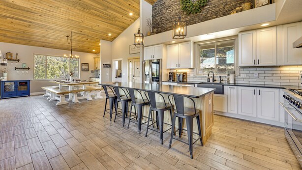 Un'ampia cucina con soffitto in legno, parete decorativa in pietra e una grande isola con sgabelli da bar.