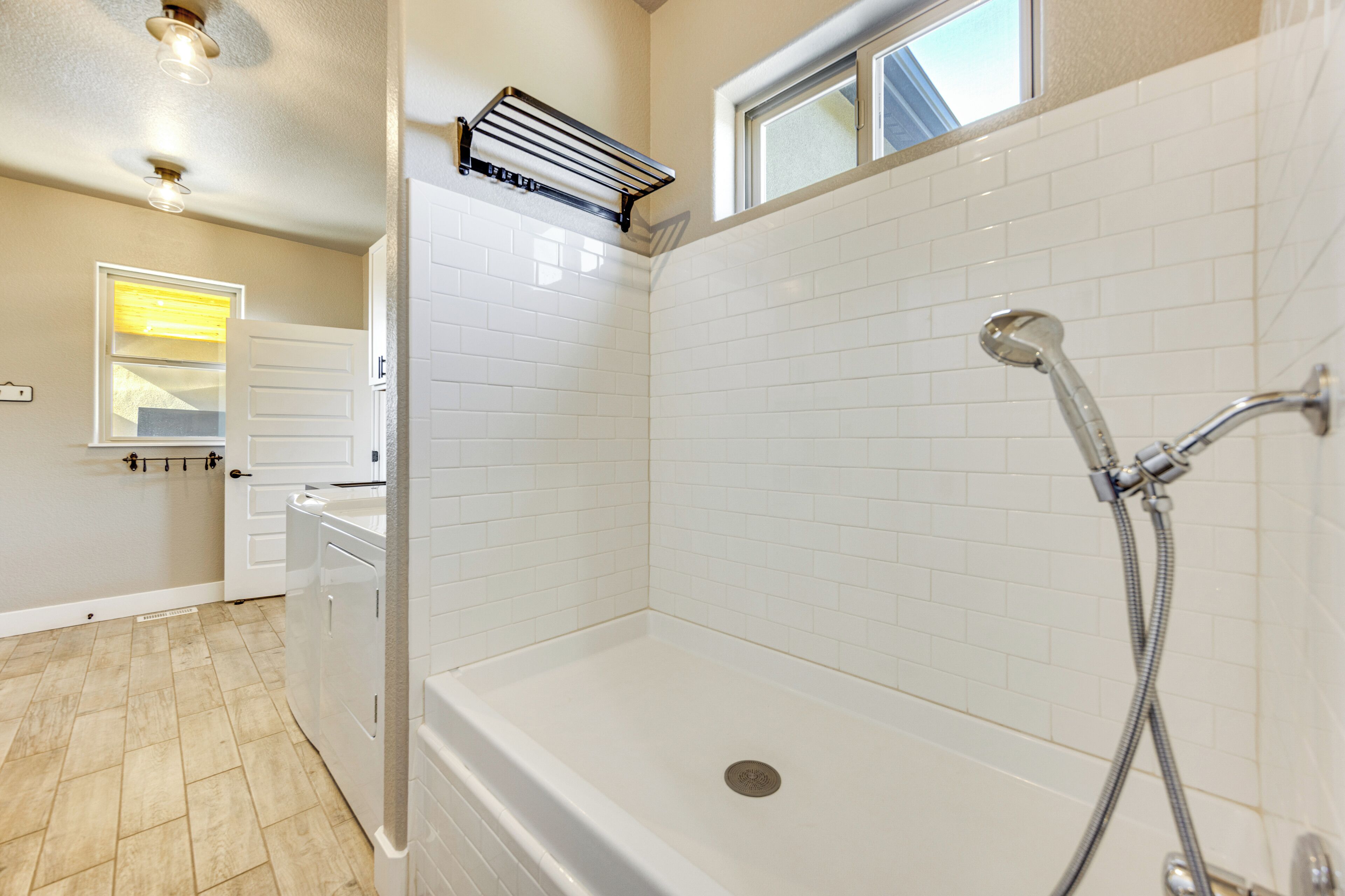 A bathroom with a shower, a window, and a towel rack.
