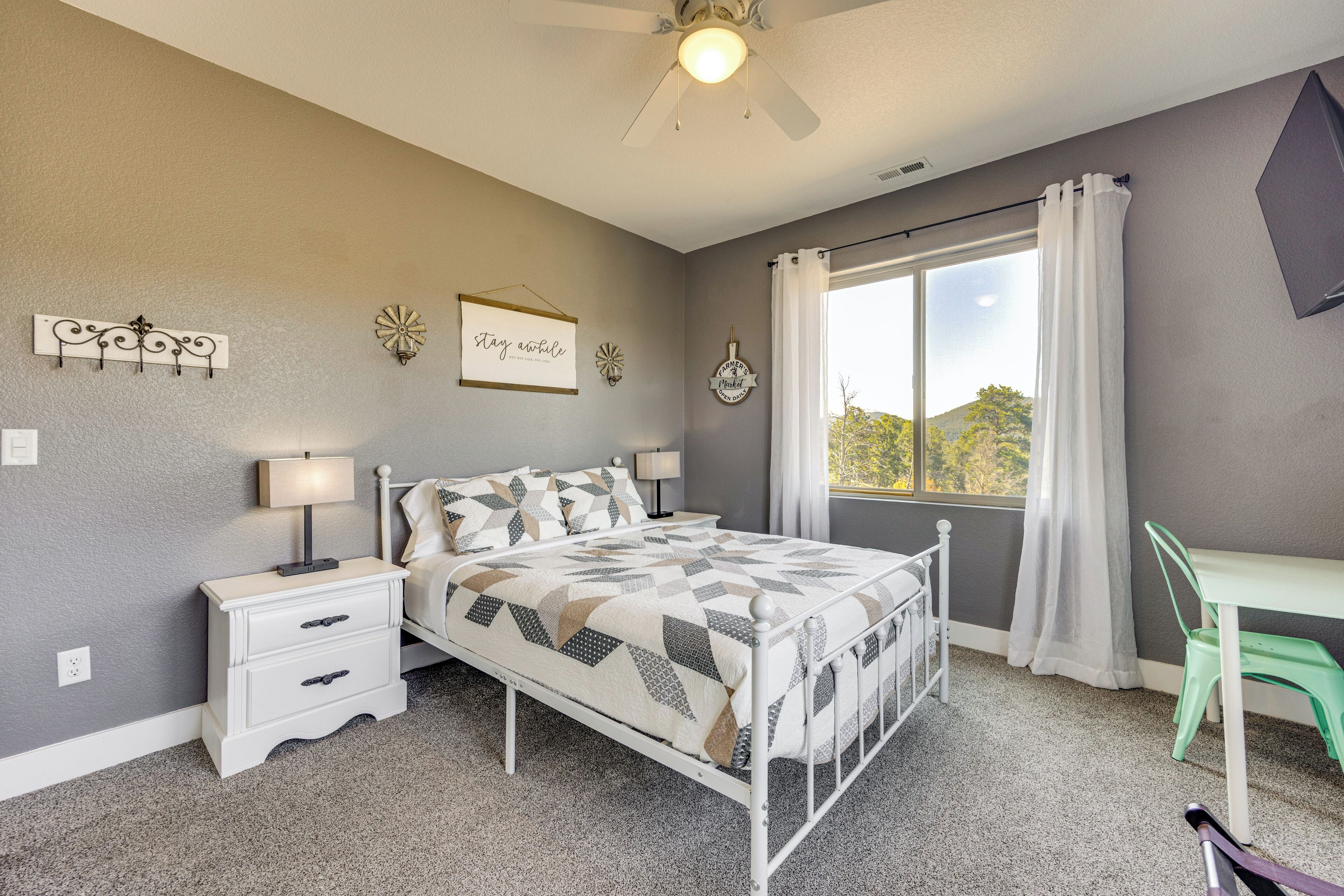 A bedroom with a bed, nightstands, a desk, and a window with curtains.