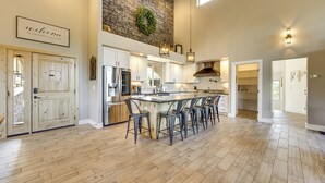 Cucina spaziosa con isola grande, pavimento in legno e parete decorativa in pietra.