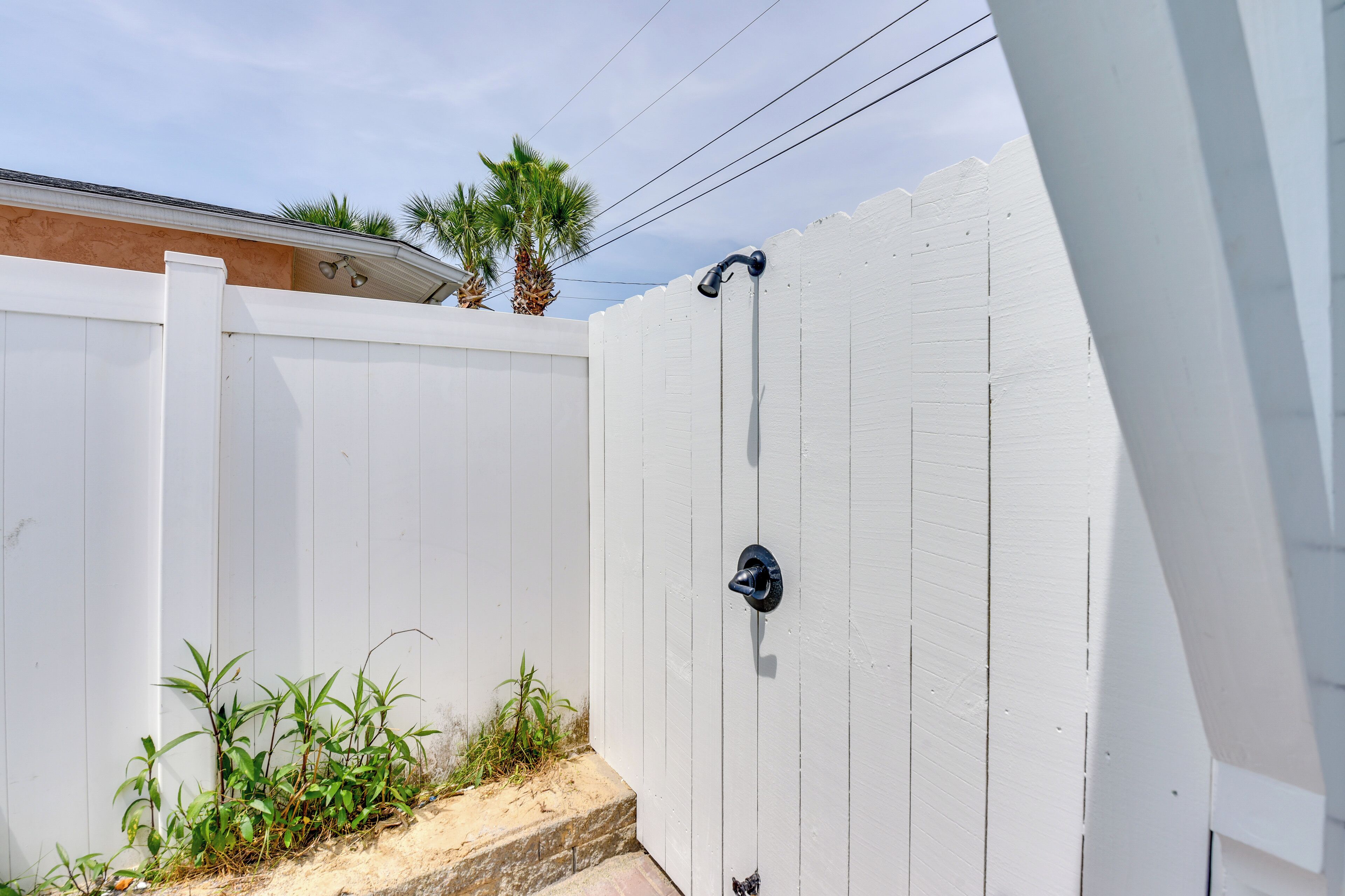 A white wooden fence with a door and a small step leading up to it.