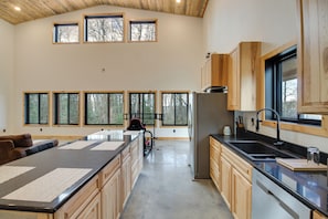 A spacious kitchen with a large island, wooden cabinets, and multiple windows offering views of the outdoors. - Minnesota Nature Escape! Lake Campbell Cabin (Bemidji)