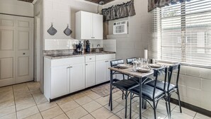 A kitchen with white cabinets, a countertop, and a dining area with a table and chairs.