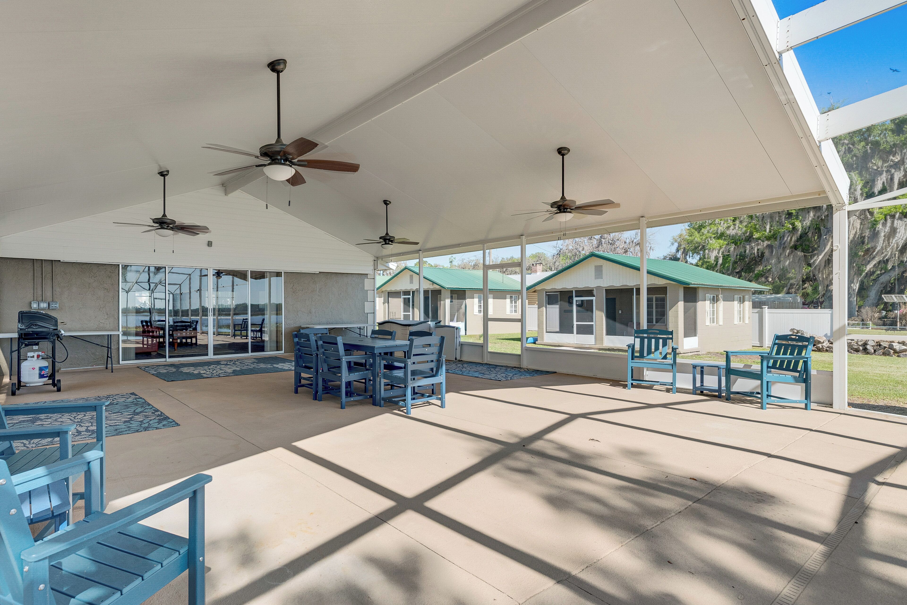 A covered outdoor area with ceiling fans, tables, chairs, and a grill.