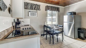 A kitchen with a stove, microwave, refrigerator, and dining area with chairs and a table.