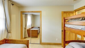 A room with two wooden bunk beds, a wooden wardrobe, a mirror, and a door leading to another room. - 40-acre Brook Park Retreat Near Lakes & Fishing! (Brook Park)