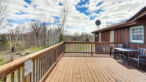 A wooden deck with a table and chairs, a satellite dish, and a view of trees and sky. - 40-acre Brook Park Retreat Near Lakes & Fishing! (Brook Park)