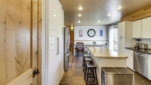 A kitchen with wooden cabinets, a central island with stools, a refrigerator, and a clock on the wall. - 40-acre Brook Park Retreat Near Lakes & Fishing! (Brook Park)