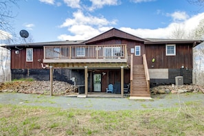 Ein zweigeschossiges Holzhaus mit Balkon, Eingangstür und einer kleinen Veranda.