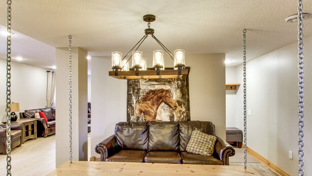A room with a wooden dining table, a brown leather sofa, a horse-themed wall mural, and a hanging light fixture. - 40-acre Brook Park Retreat Near Lakes & Fishing! (Brook Park)