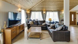 A living room with a wooden ceiling, leather sofas, a wooden coffee table, a flat-screen TV, and a cabinet. - 40-acre Brook Park Retreat Near Lakes & Fishing! (Brook Park)