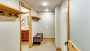 A hallway with a wooden bench, a coat rack, and a door leading to a bathroom. - 40-acre Brook Park Retreat Near Lakes & Fishing! (Brook Park)