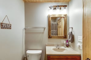 A bathroom with a toilet, a sink, a mirror, and a shower curtain. - 40-acre Brook Park Retreat Near Lakes & Fishing! (Brook Park)